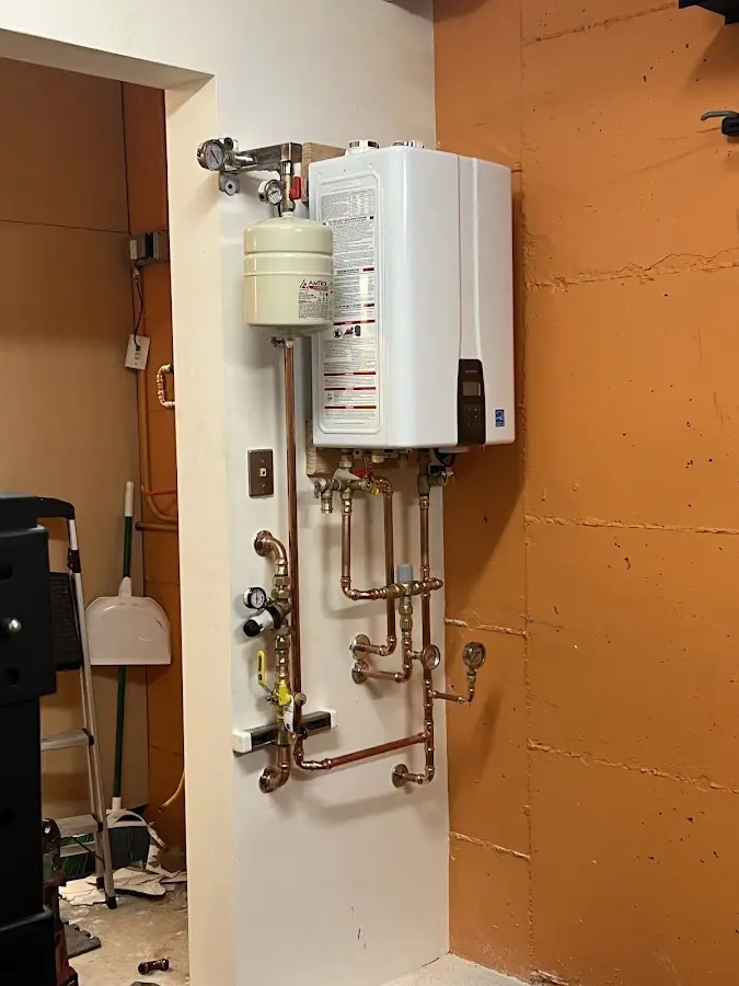 Plumbing technician inspecting water heater connections in Moreau